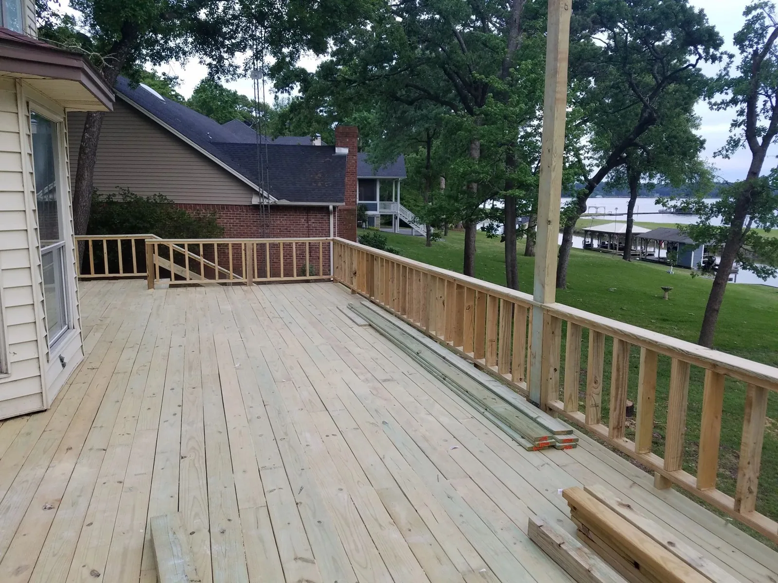 Wood deck and railing beside a home overlooking the water
